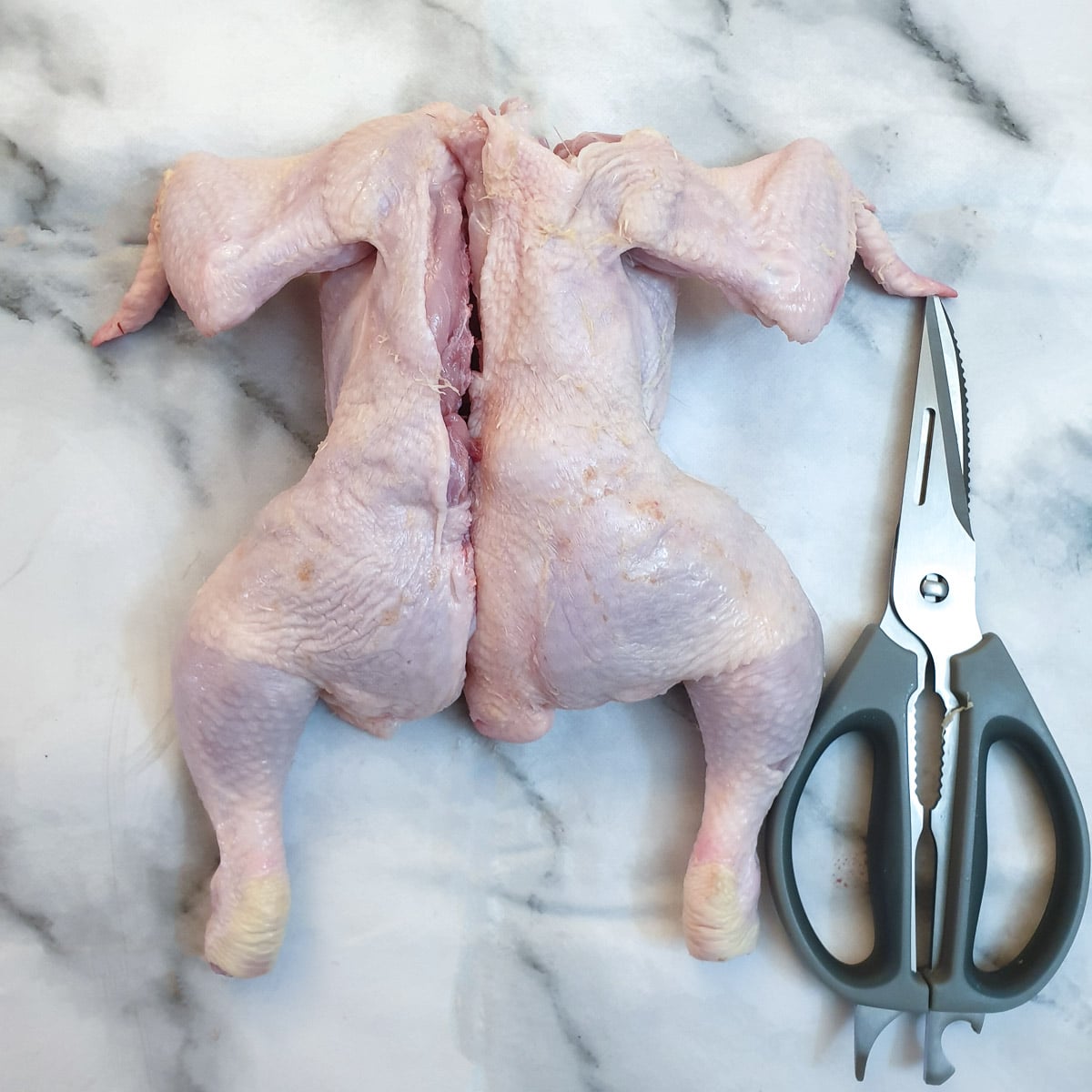 A chicken cut in half down one side of the backbone.
