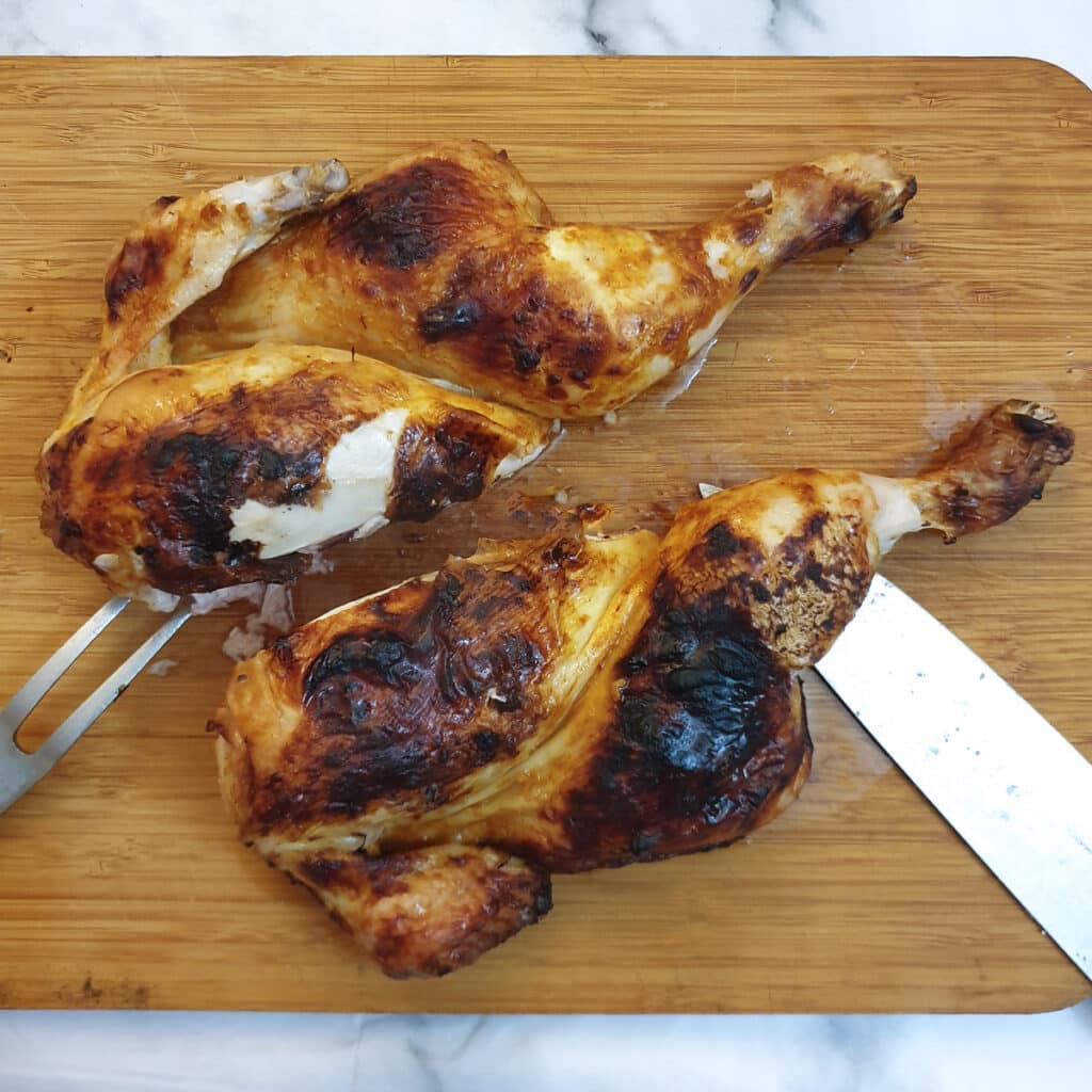 A roasted spatchcock chicken cut in half through the breastbone.