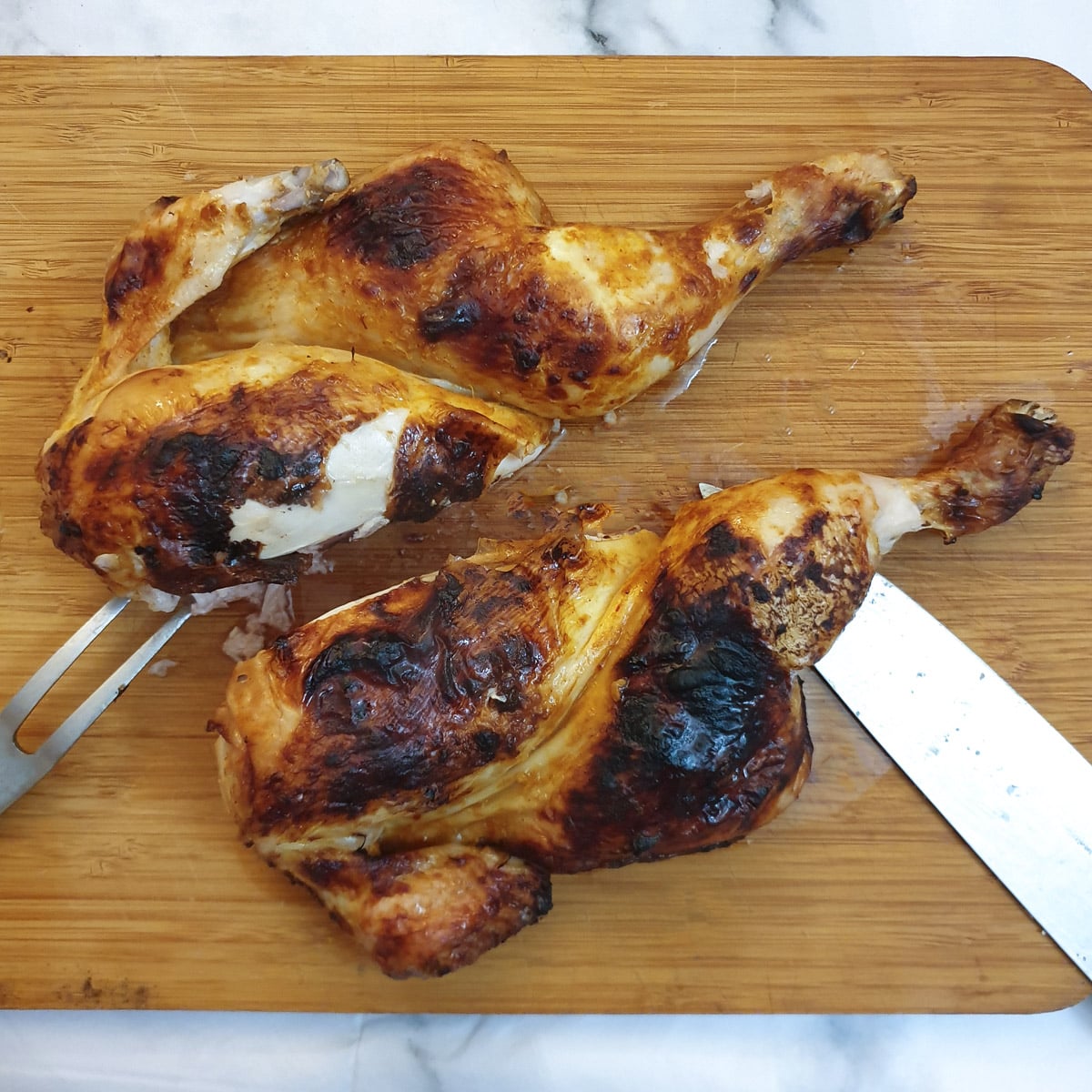 A roasted spatchcock chicken cut in half through the breastbone.