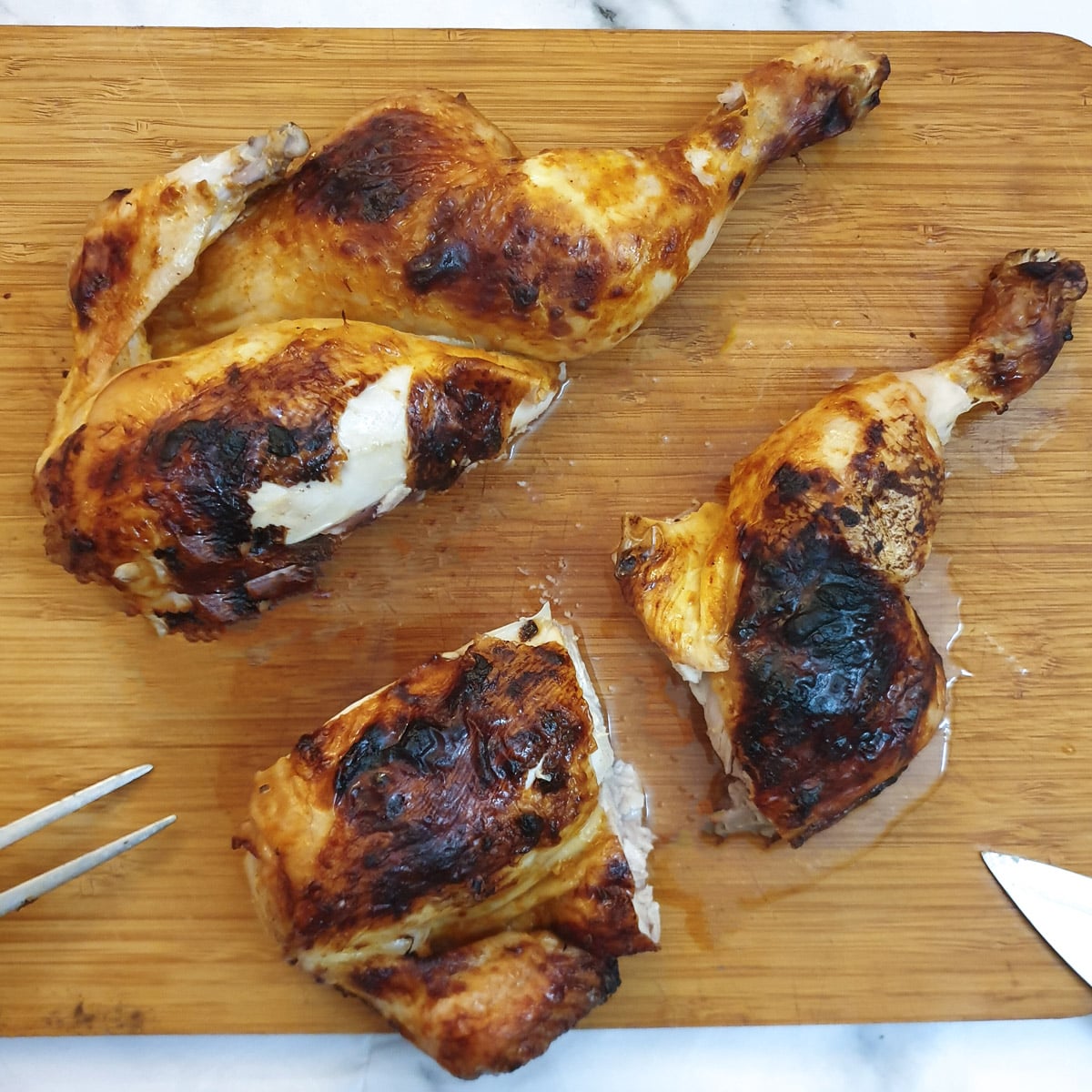 A roasted spatchcock chicken being cut into quarters.