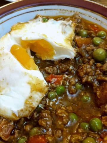 A dish of lamb keema topped with a baked egg.