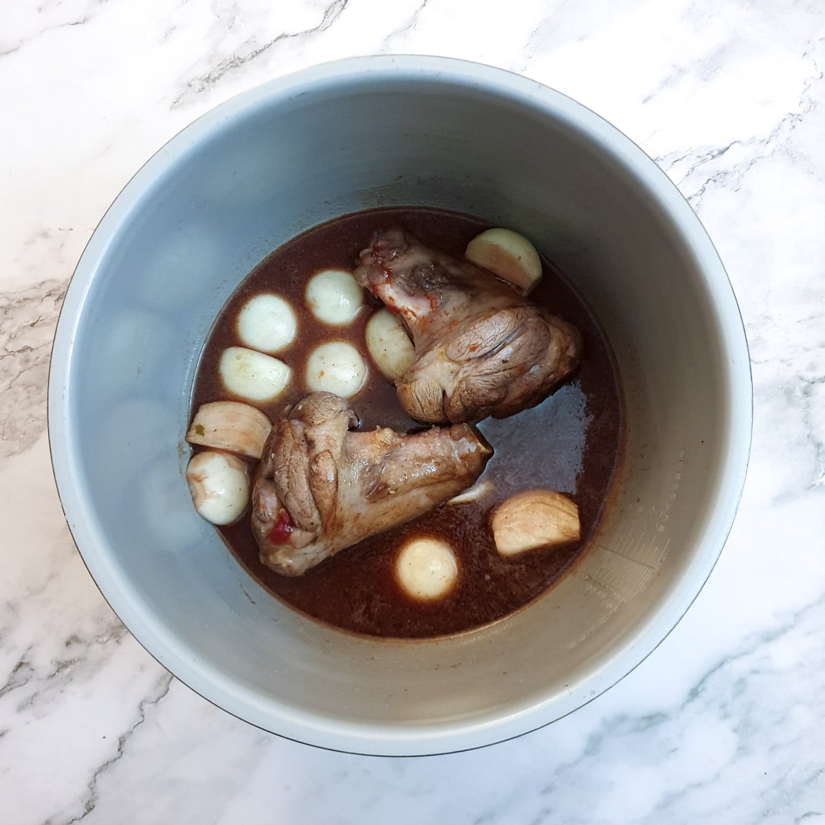 Stock, red wine and onions added to the lamb shanks.