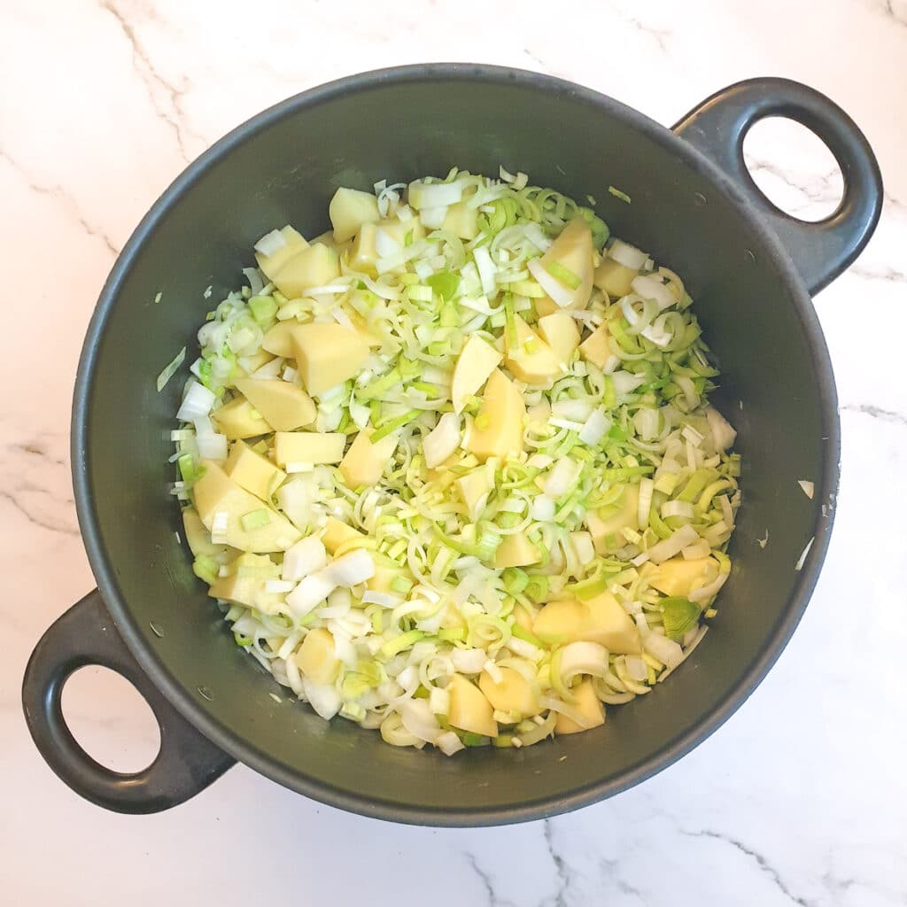 Chopped potatoes, leeks and onions in a saucepan.