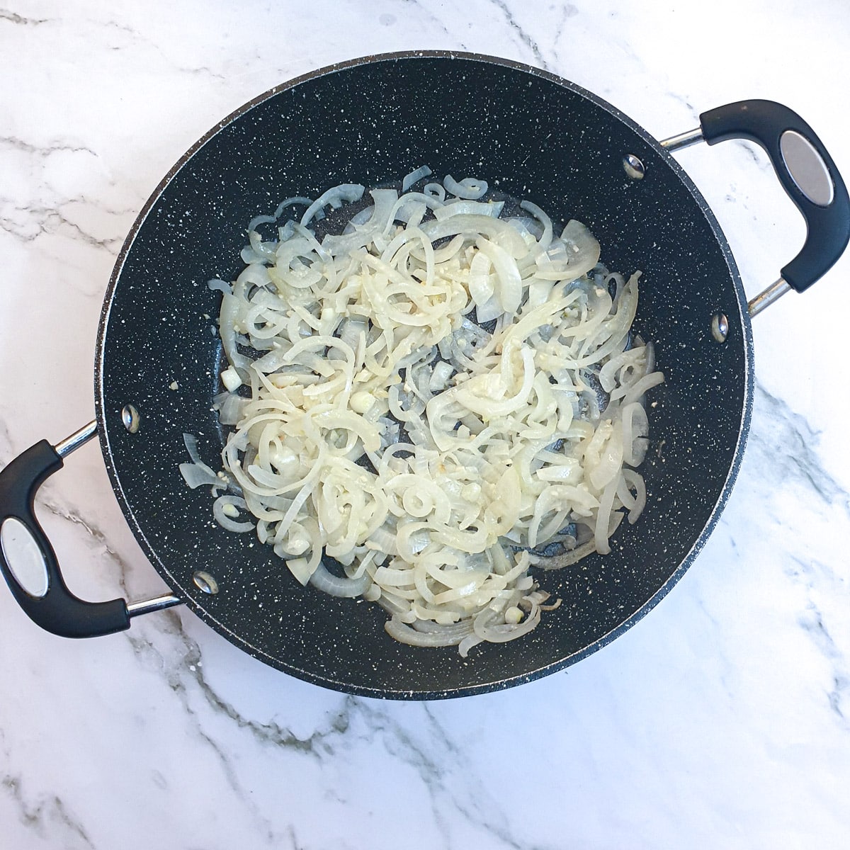 Sliced onions being fried in butter with the addition of thyme and garlic.