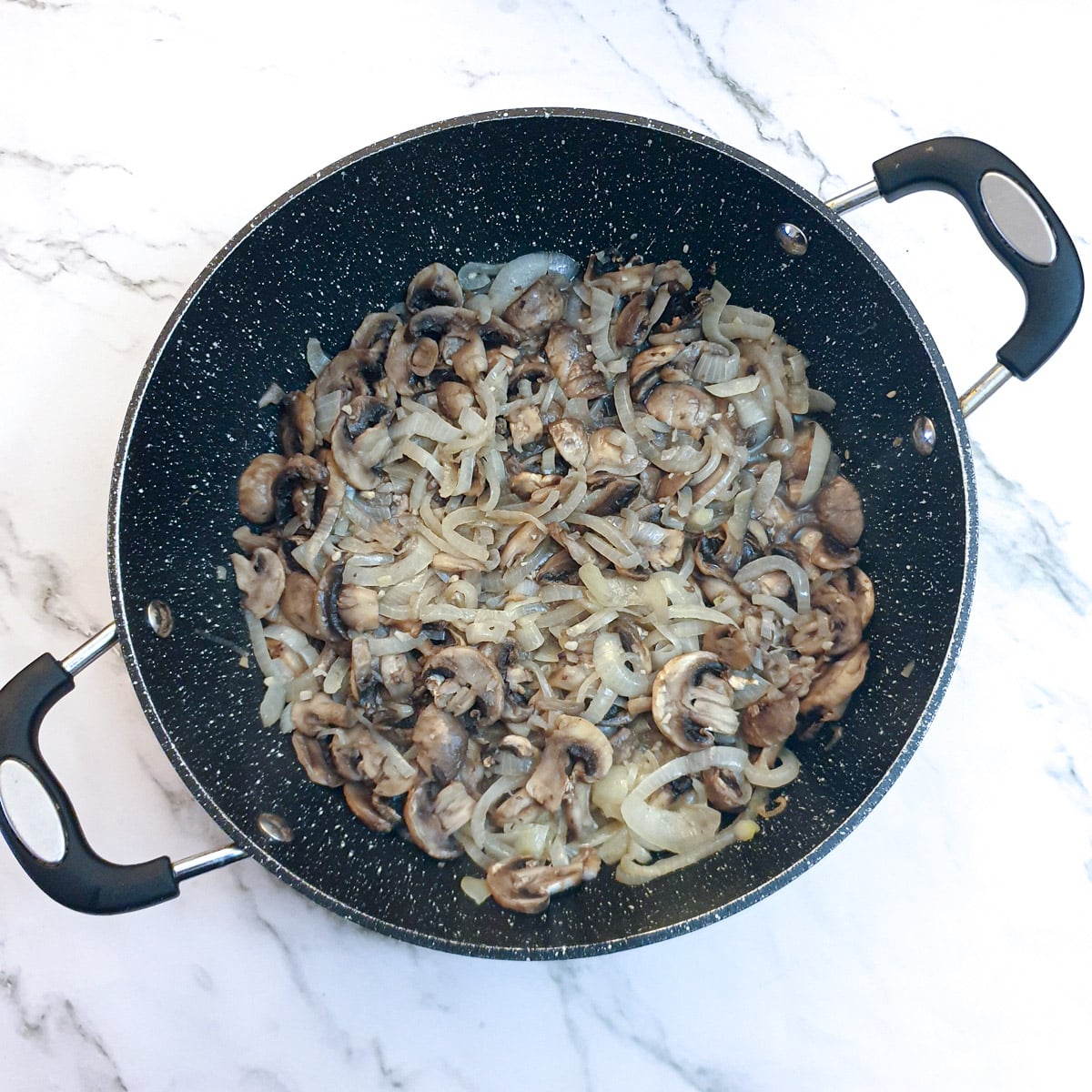 Mushrooms fried with the onios in a frying pan.