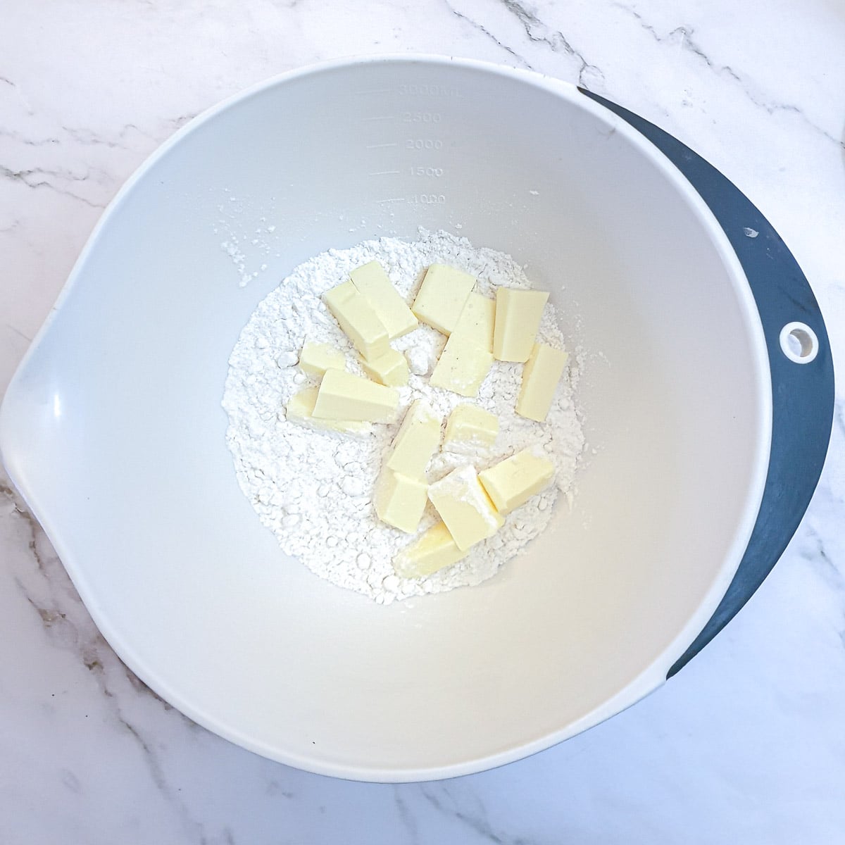 Cubed butter and flour in a mixing bowl.