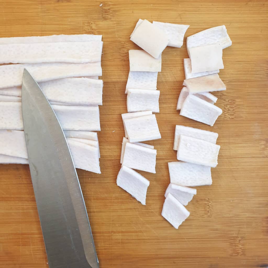 Strips of pork skin being cut into shorter lengths.
