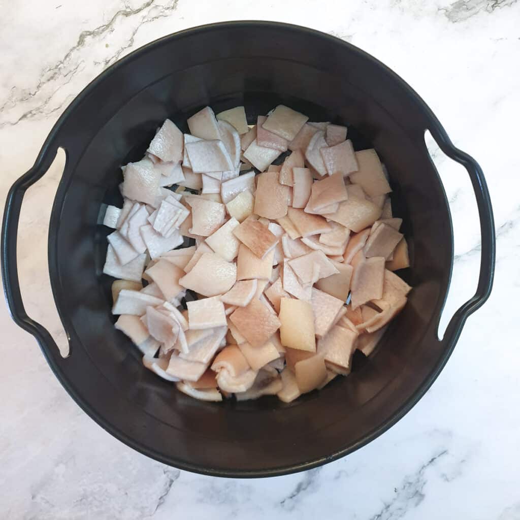 Pieces of pork skin in a Ninja multi-cooker basket.