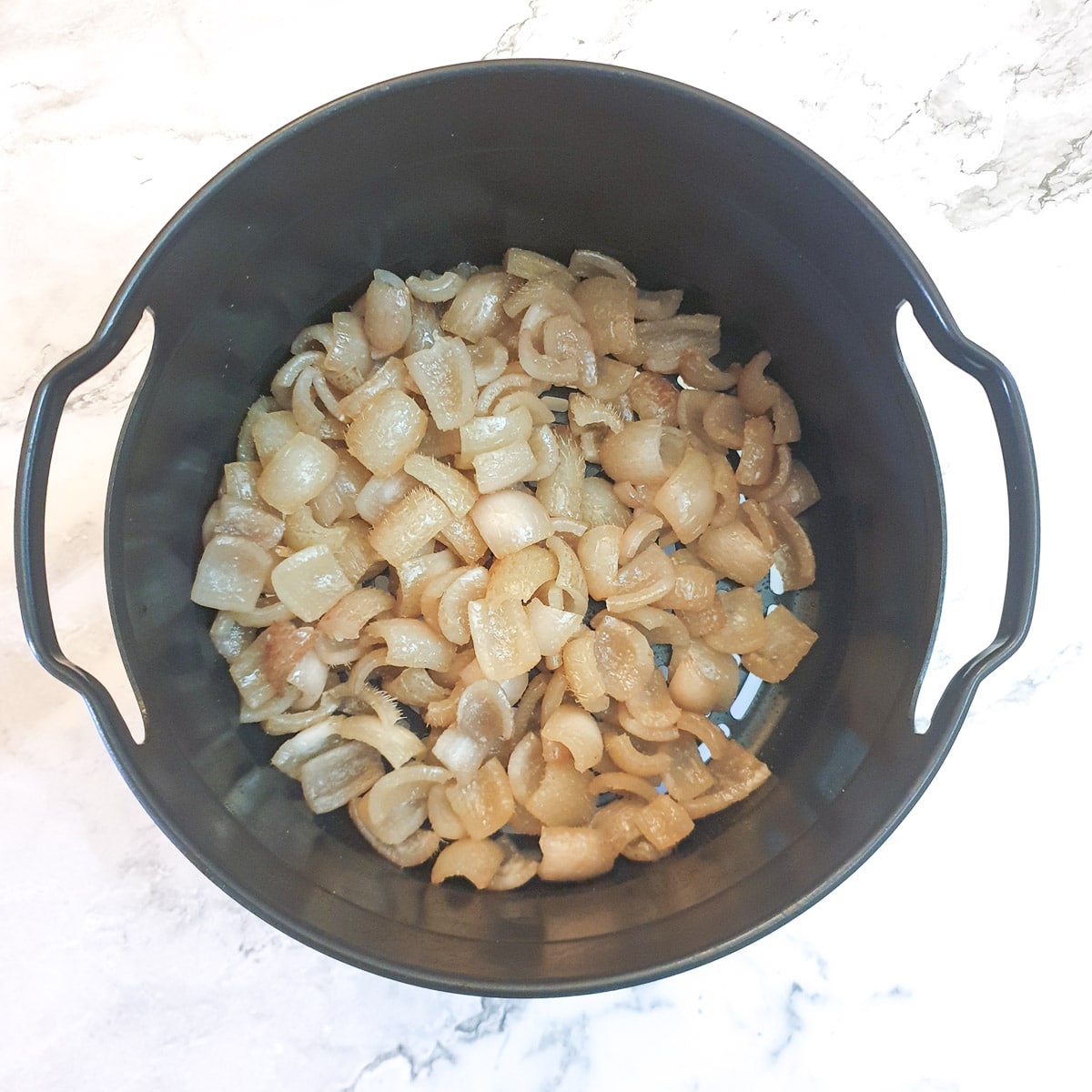 Pork scratchings in an air fryer basket after having been cooked for 10 minutes.