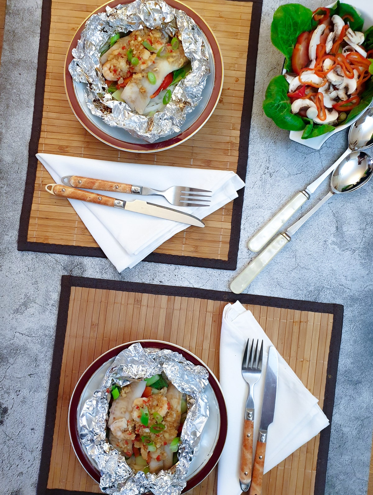 Overhead shot of a table with opened Thai fish parcels on plates.