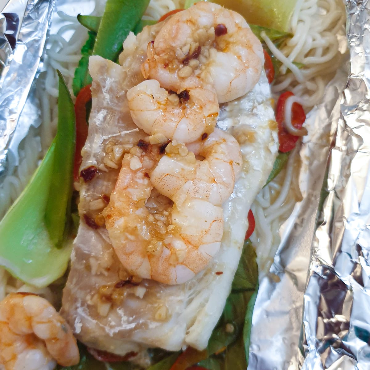 An opened Thai fish parcel showing the cooked fish and prawns.