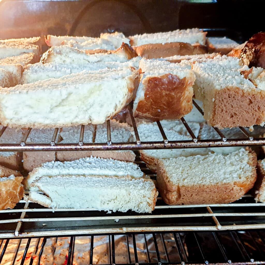 Slices of buttermilk rusks on oven racks drying in the oven.
