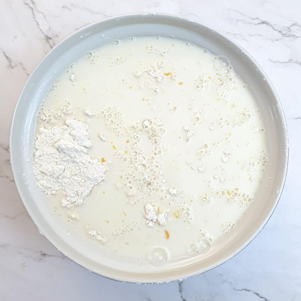 Egg and buttermilk in a bowl with flour.