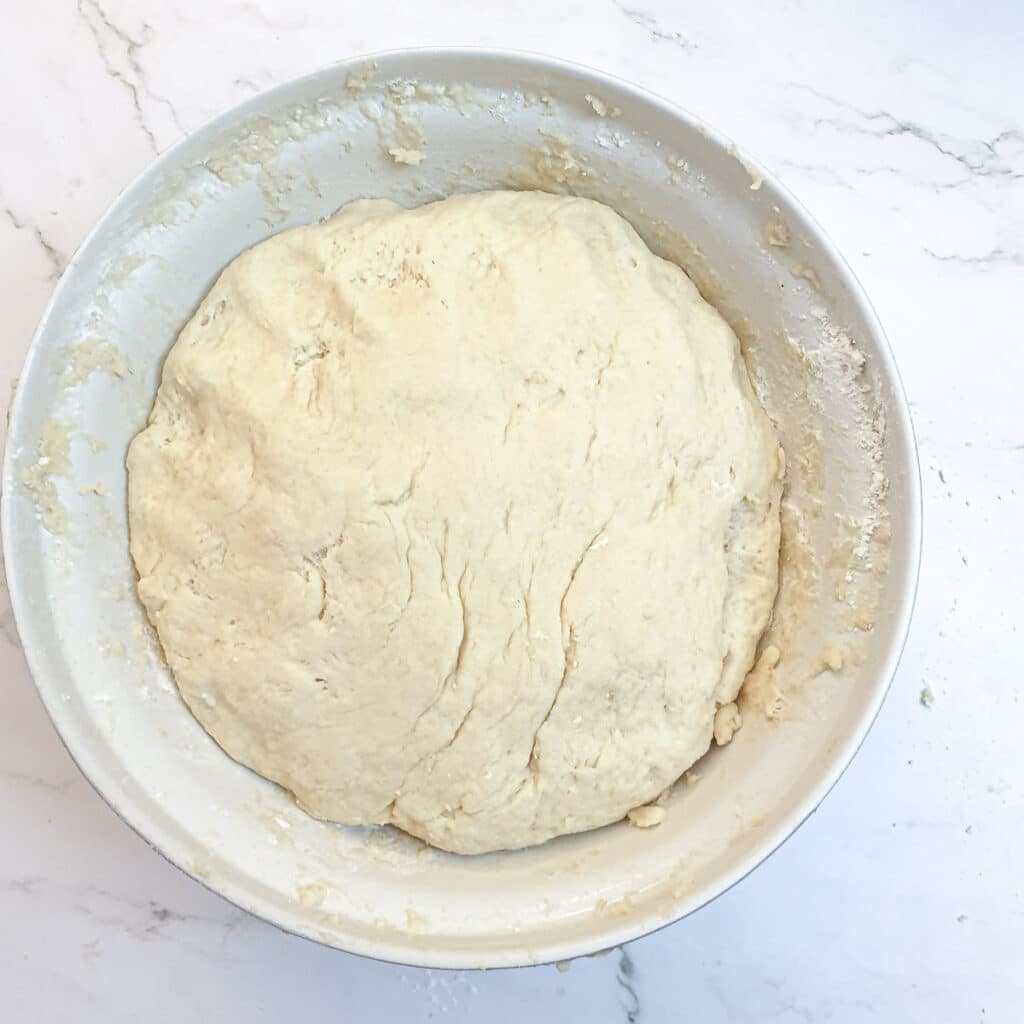 A large mixing bowl with a ball of fully mixed buttermilk rusk dough.