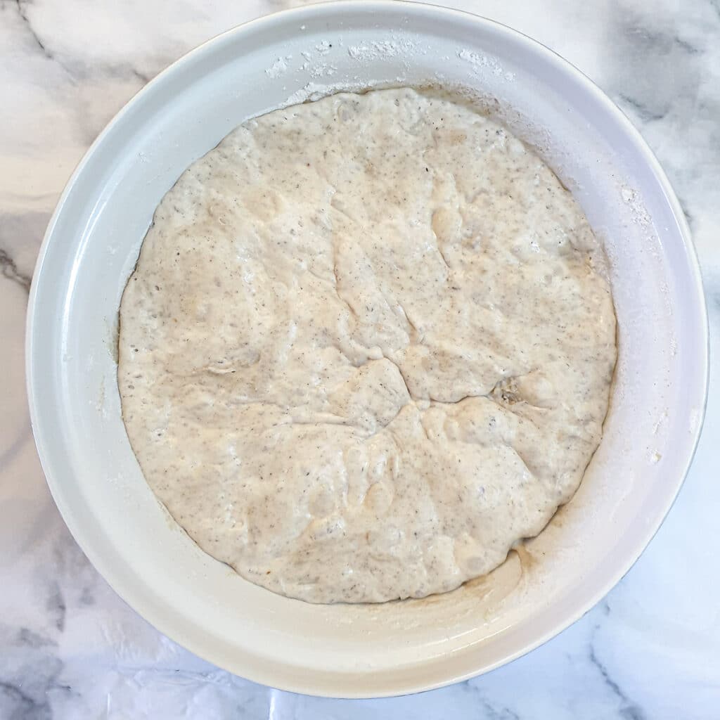 A bowl containing risen cheese and onion dough.