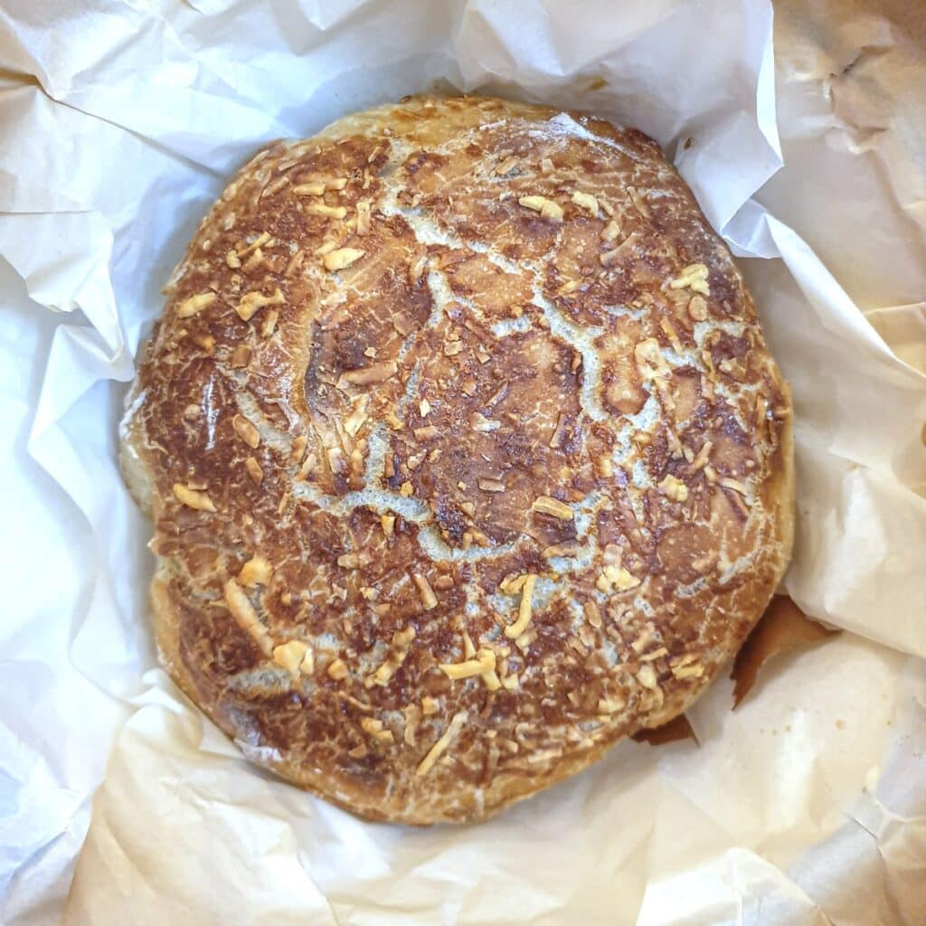 A golden brown cheese and onion loaf in a nest of baking parchment.