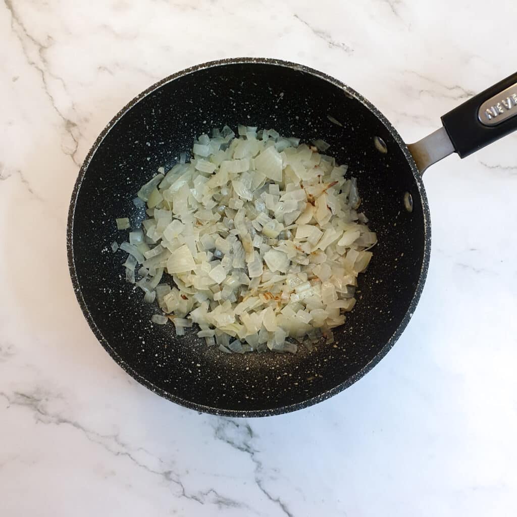 Chopped onions frying in a pan.