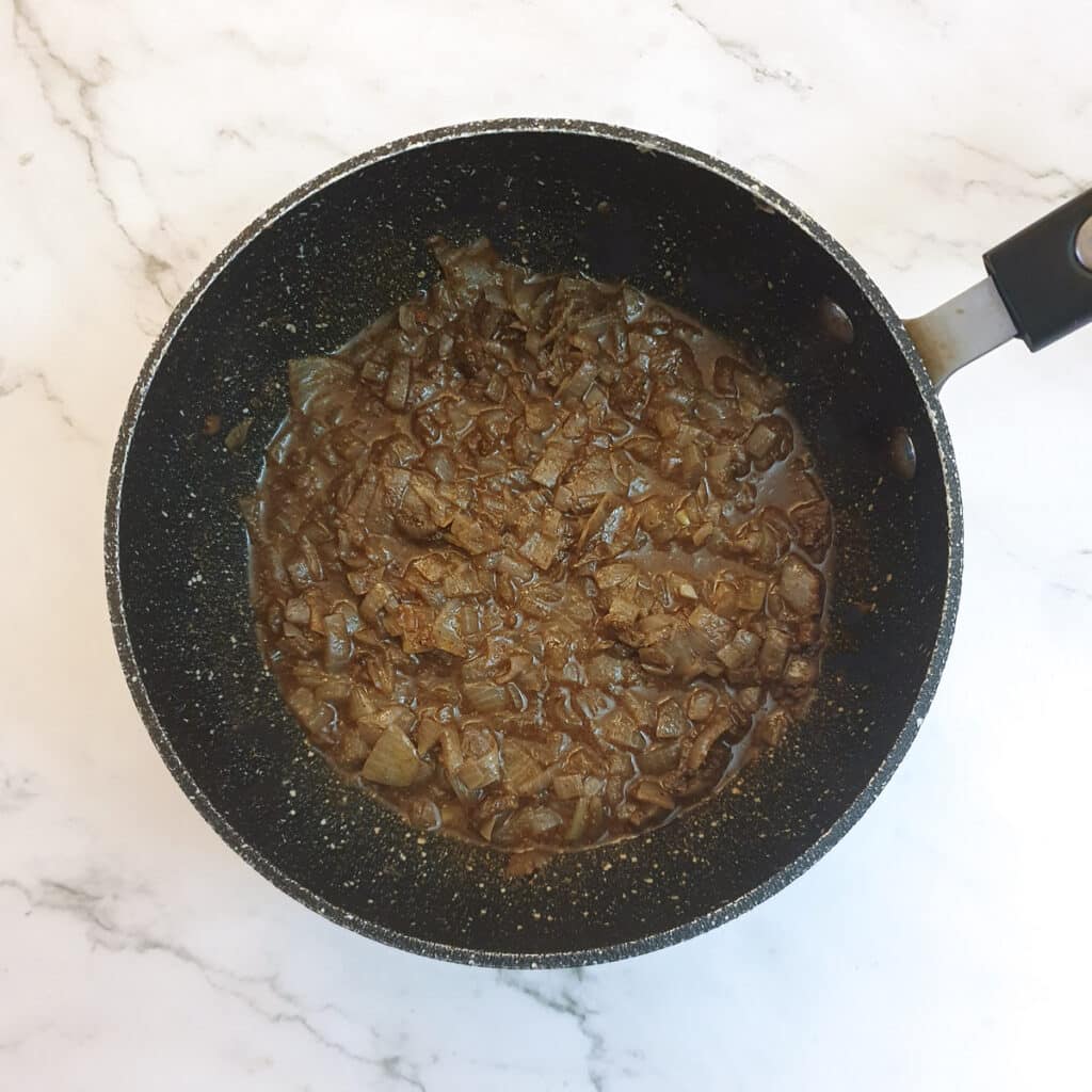 Canned sweetcorn liquid added to onions  and spices in a frying pan.