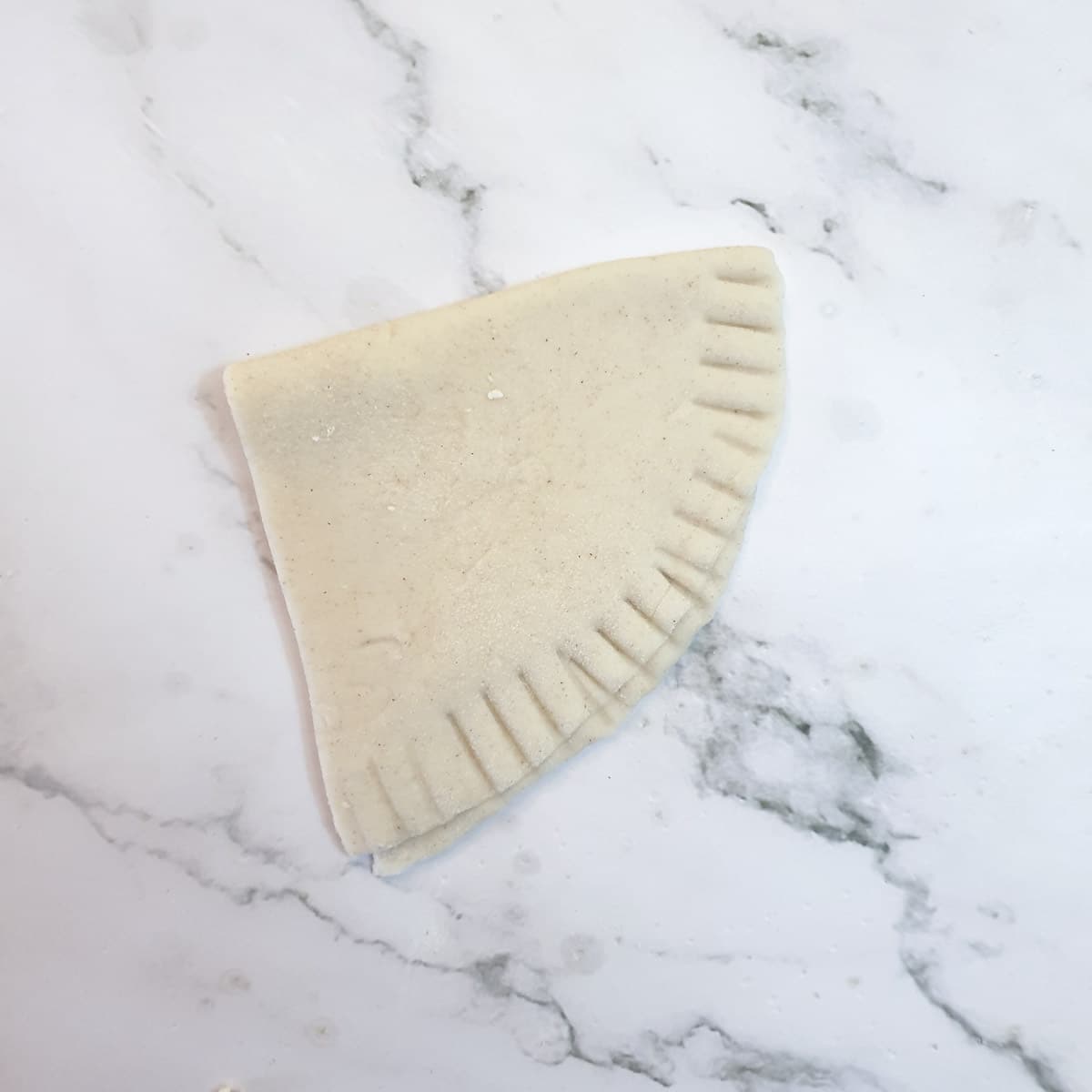 A semi-circle of pastry folded in half and sealed on one side, leaving the top open.