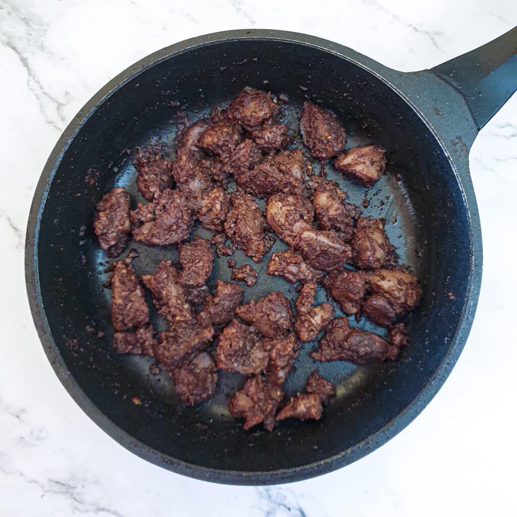 Chicken livers in a frying pan with the addition of spices.
