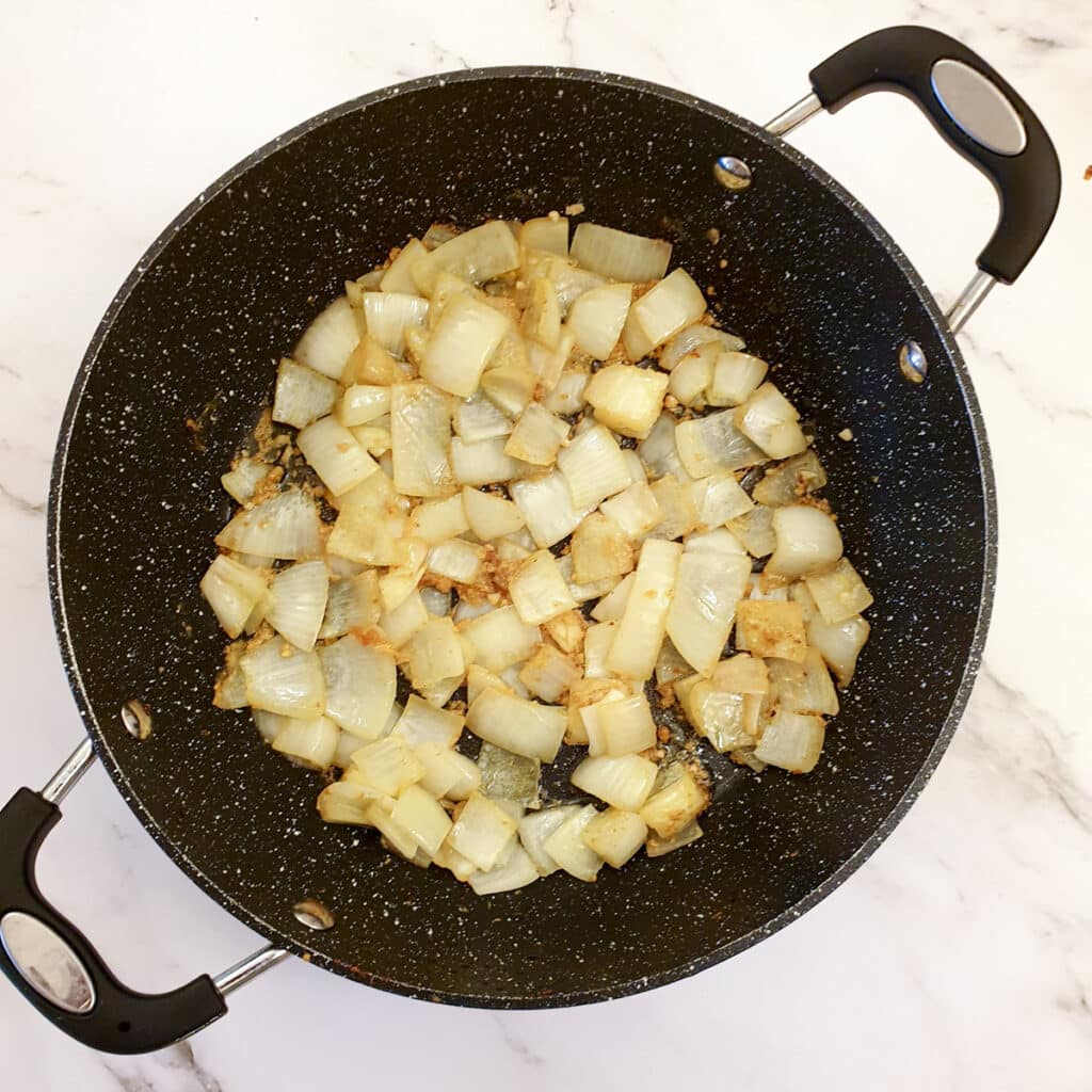 Onions and garlic frying in a nixture of butter and oil in a frying pan.