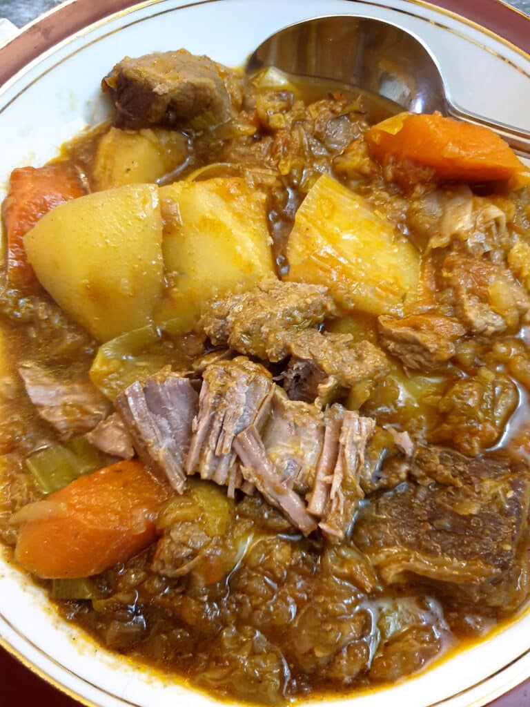 Close up of a dish of lamb stew, showing how the meat falls apart.