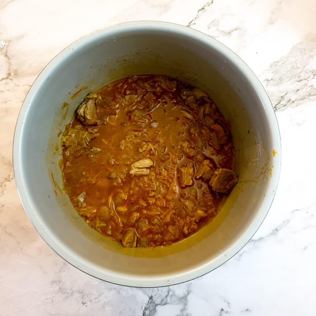 Lamb and grated vegetables in a pressure cooker after having been cooked for 15 minutes.