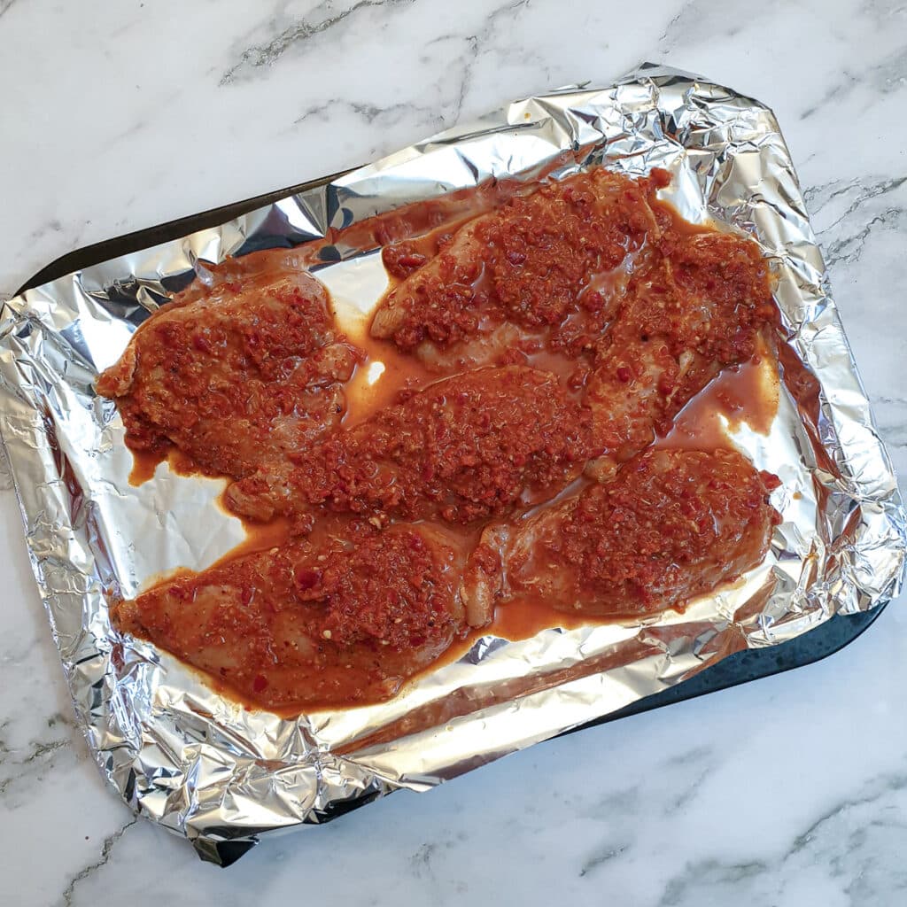 Slices of peri peri chicken on a baking tray.