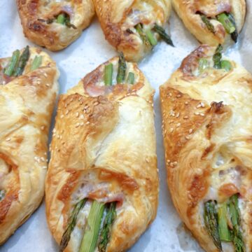 6 puff pastry asparagus and ham wraps on a plate.