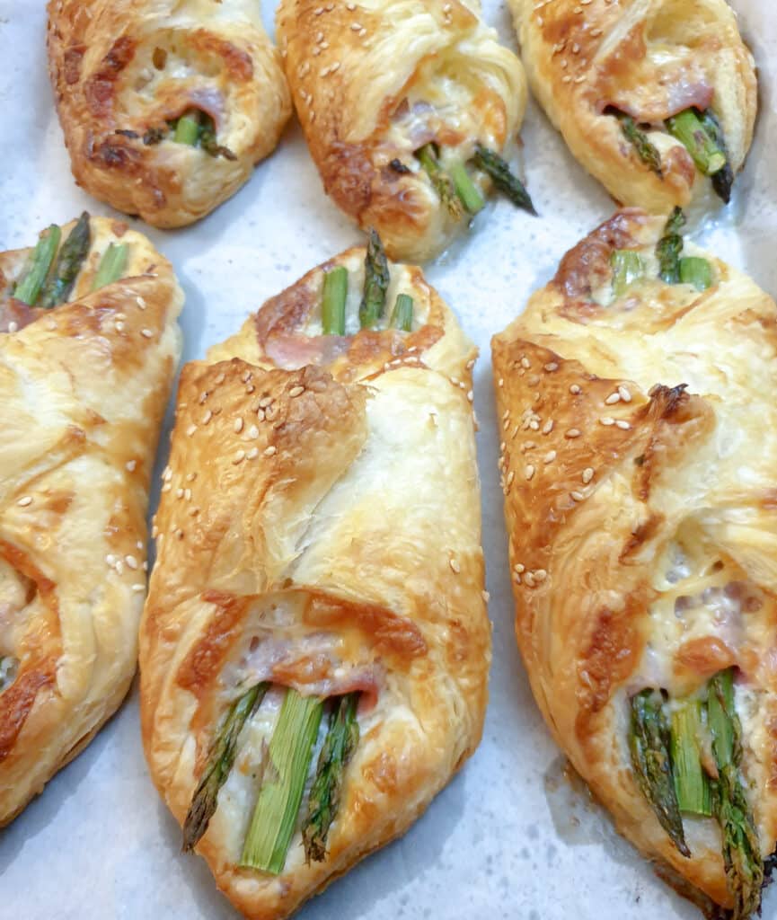 6 puff pastry asparagus and ham wraps on a plate.