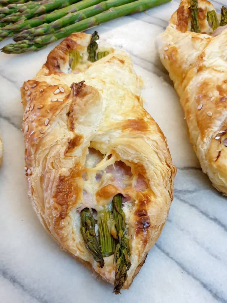 Close up of asparagus and ham wrapped in lightly browned puff pastry.