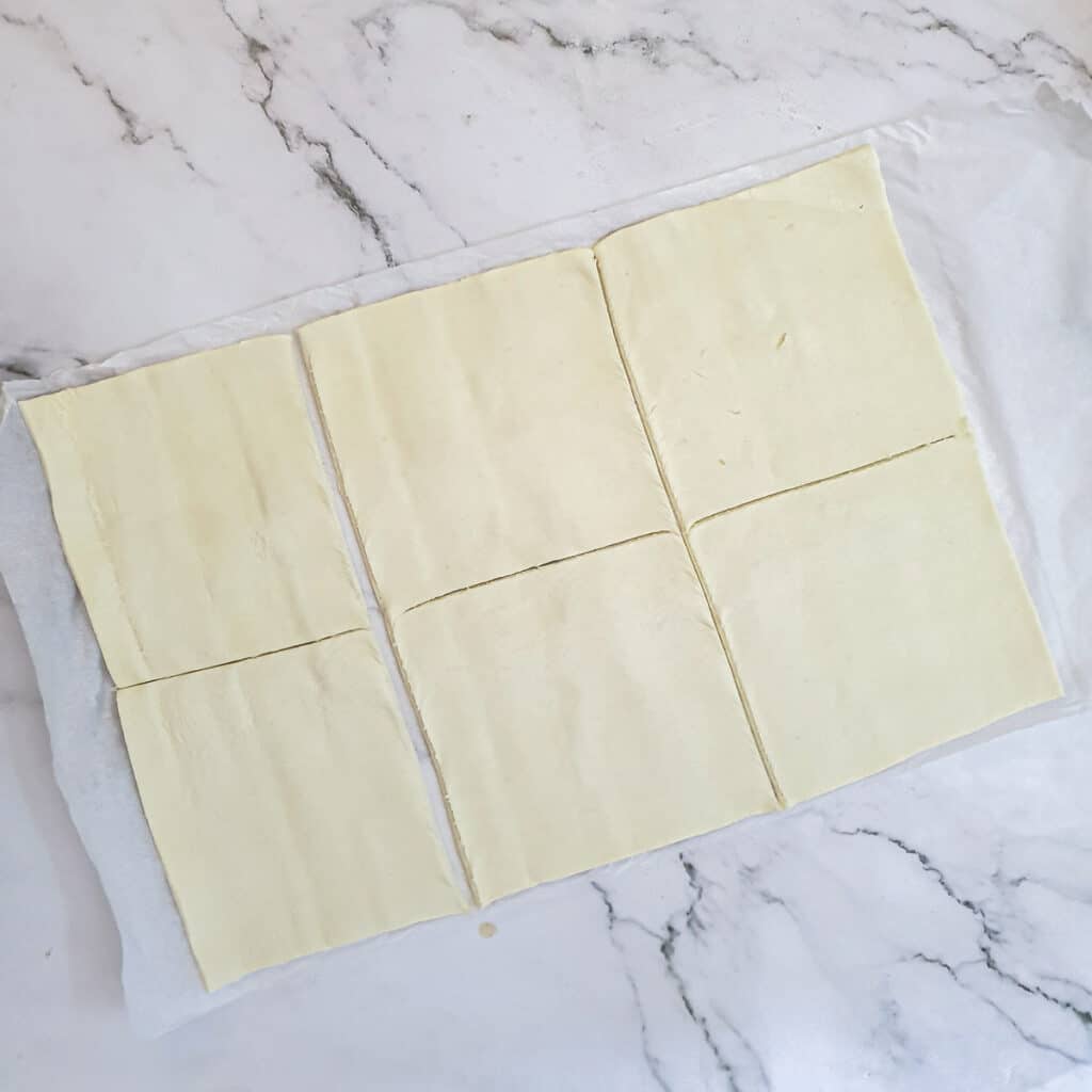 A sheet of puff pastry cut into 6 squares.