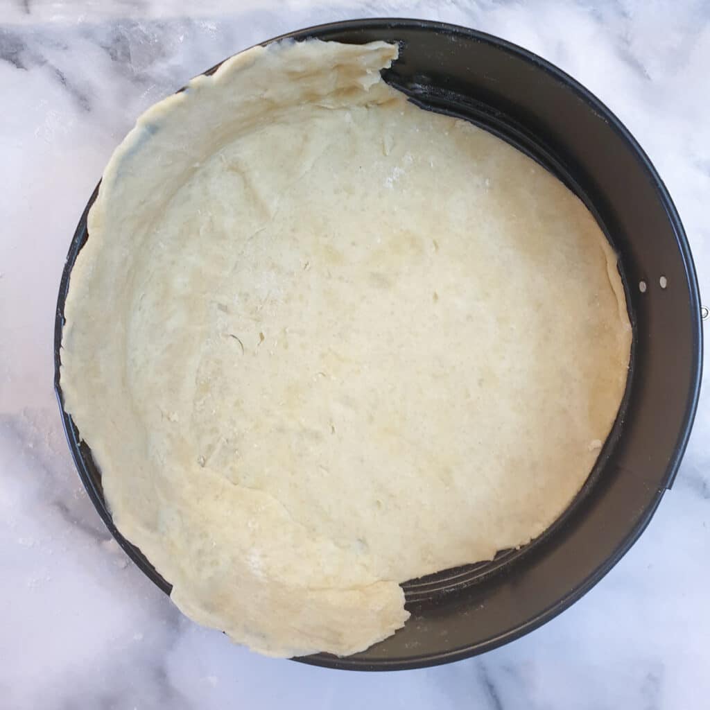 A springform pan with the base and half of the side lined with pastry.