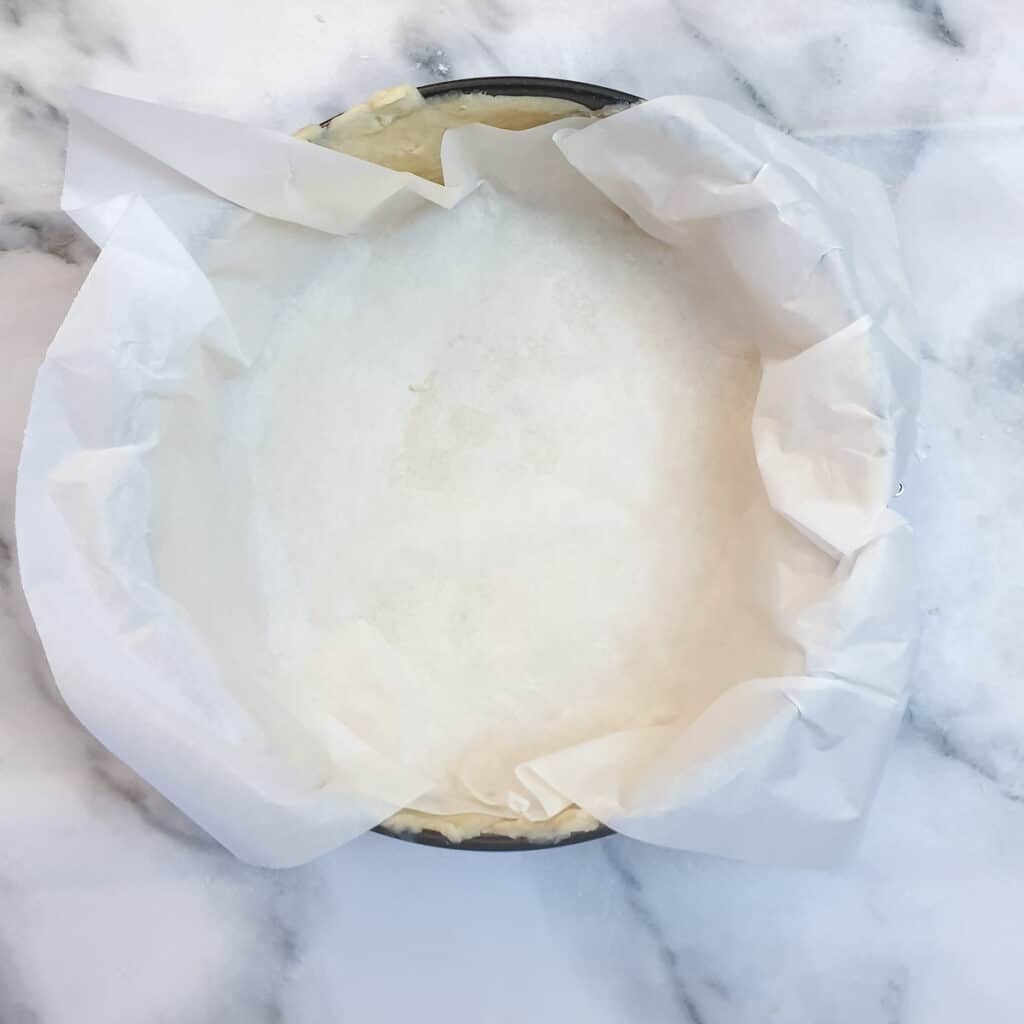 Baking parchment covering pastry in a springform pan.