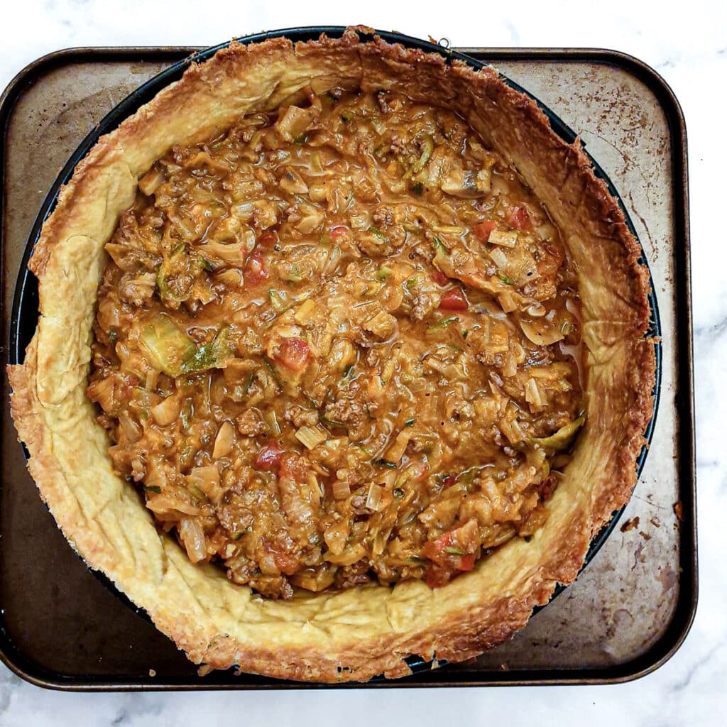 A baked pastry case filled with beef and onion filling.