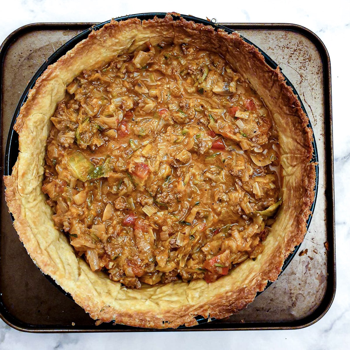 A baked pastry case filled with beef and onion filling.