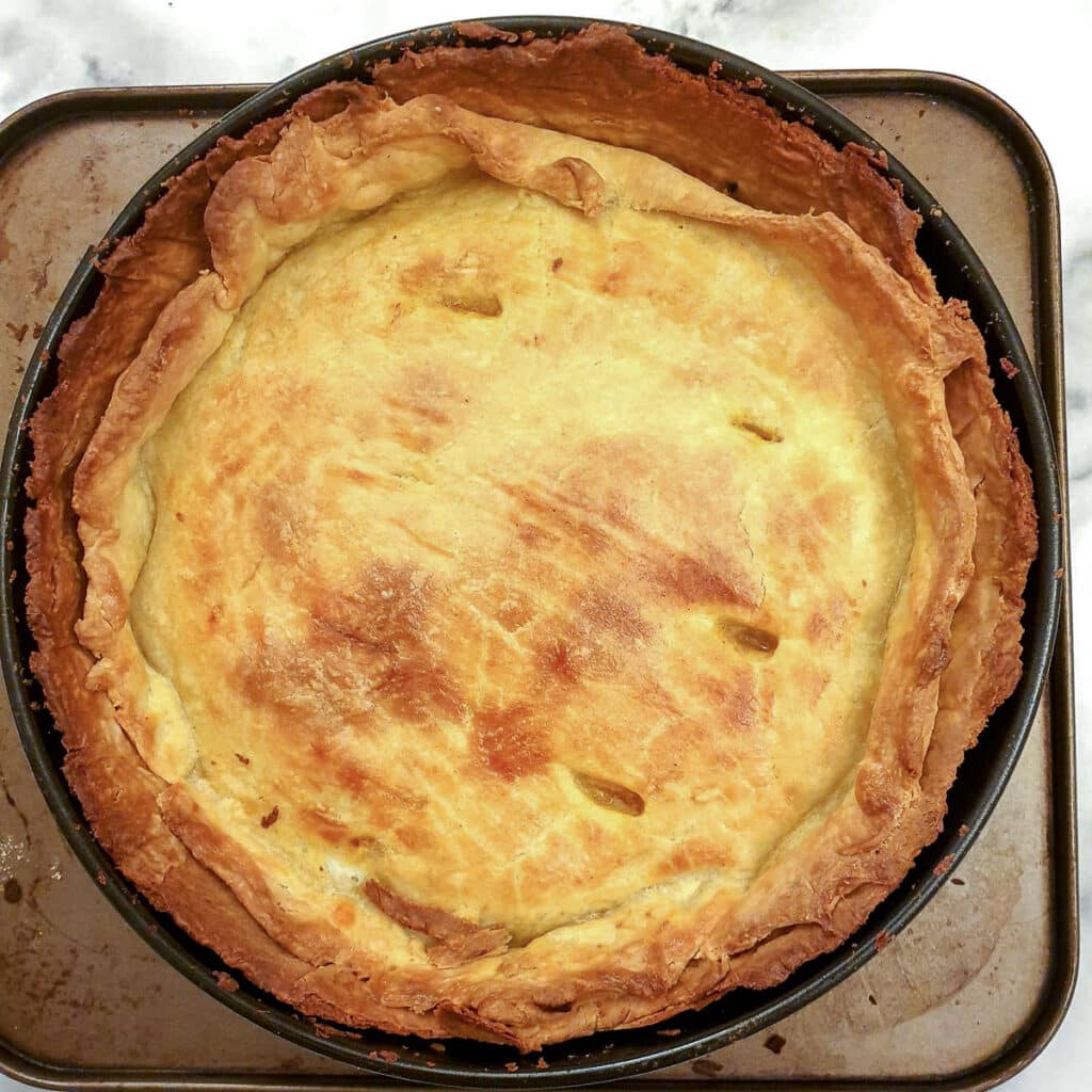 A fully cooked beef and onion pie in a spring form pan.,