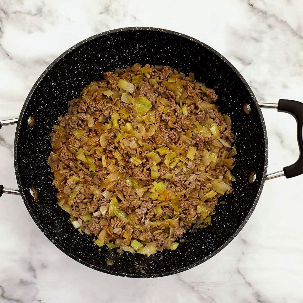 Chopped mushrooms with mince and onions in a frying pan.