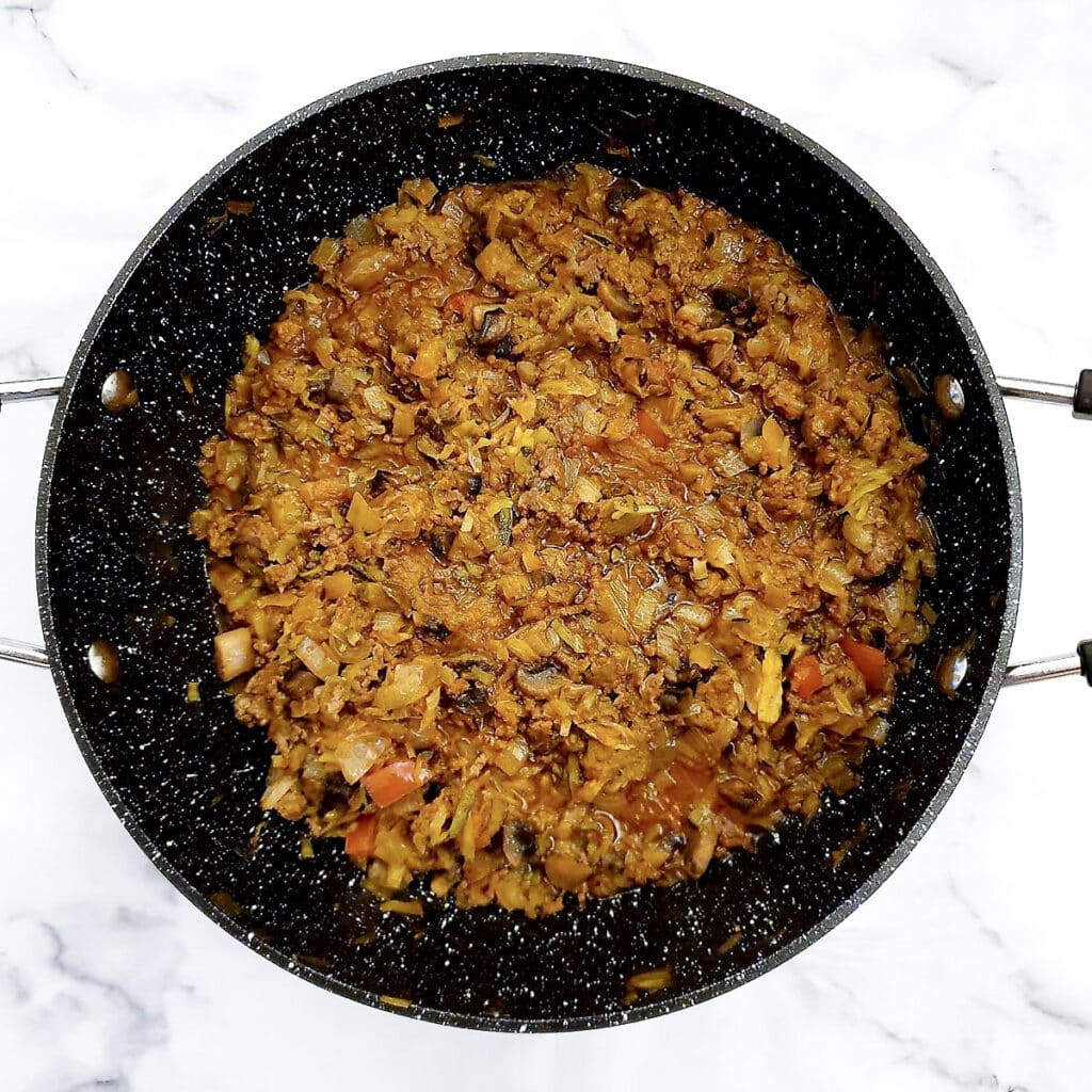 A frying pan with the cooked filling for beef and onion pie.