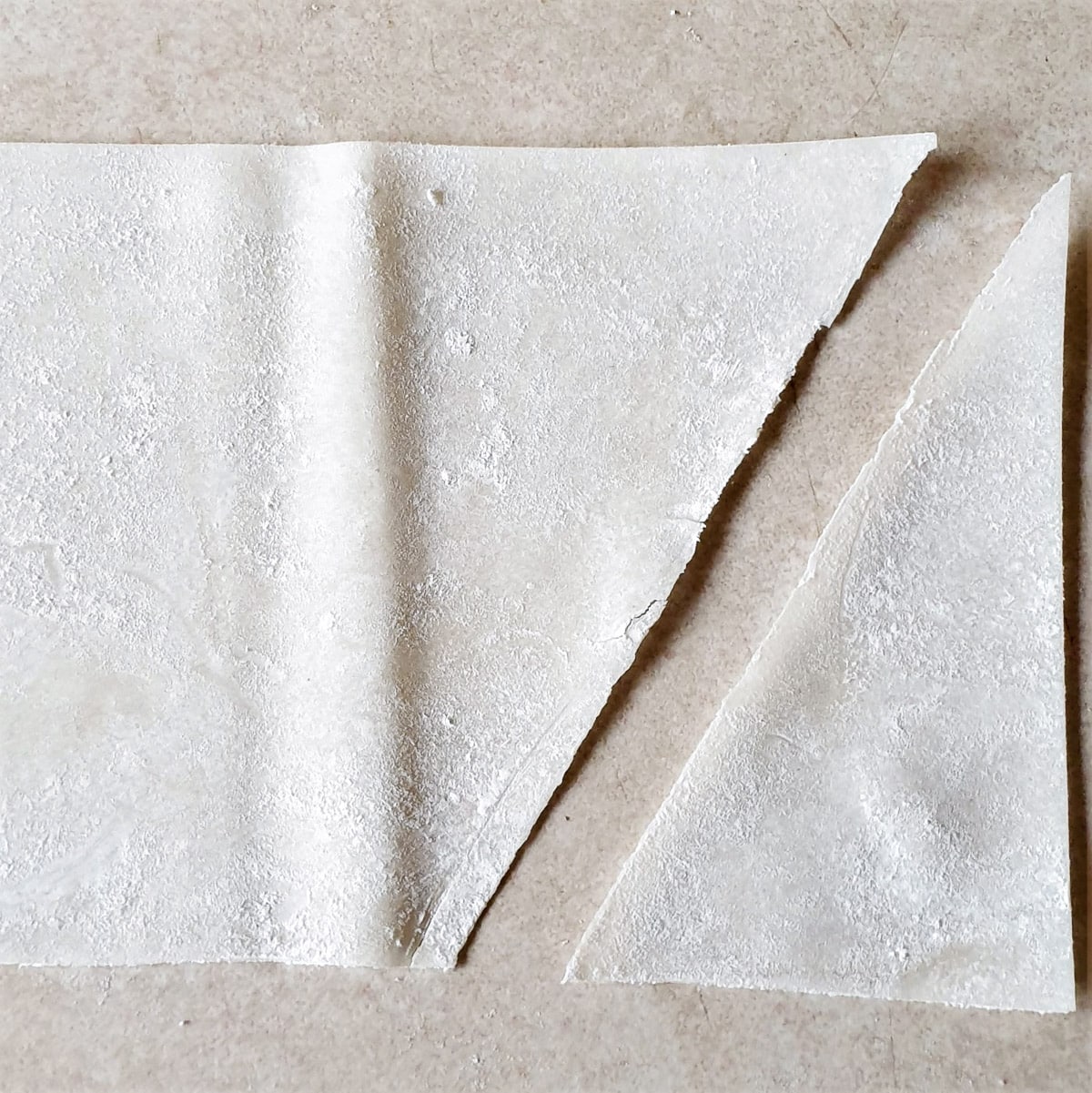 A strip of phyllo pastry with a triangular piece cut from the end.