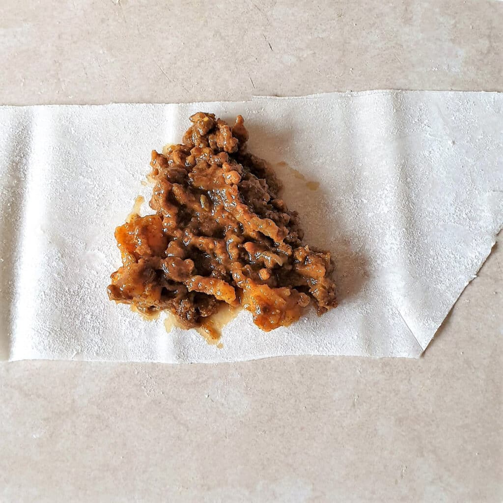 A spoonful of samosa filling on a piece of phyllo pastry.