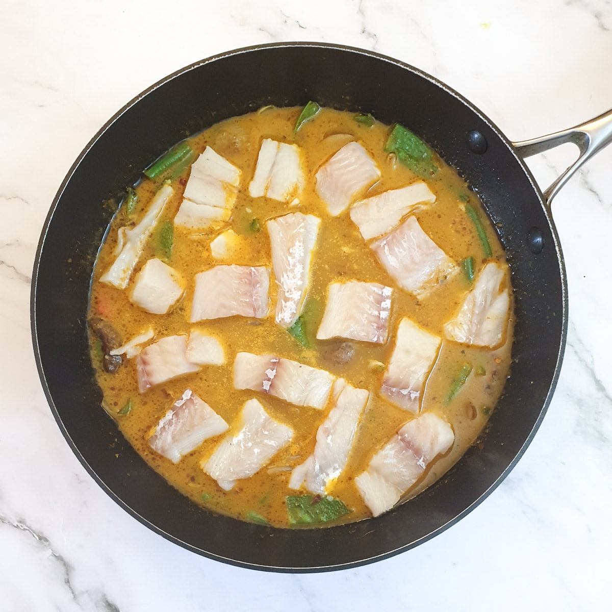 Pieces of white fish nestled in the Thai curry sauce.