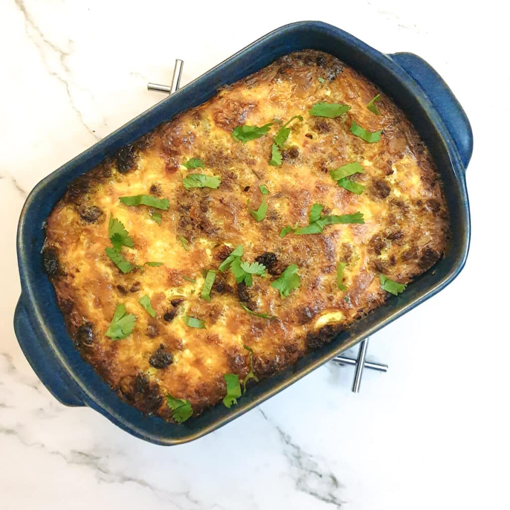 The completed dish of bobotie garnished with coriander.