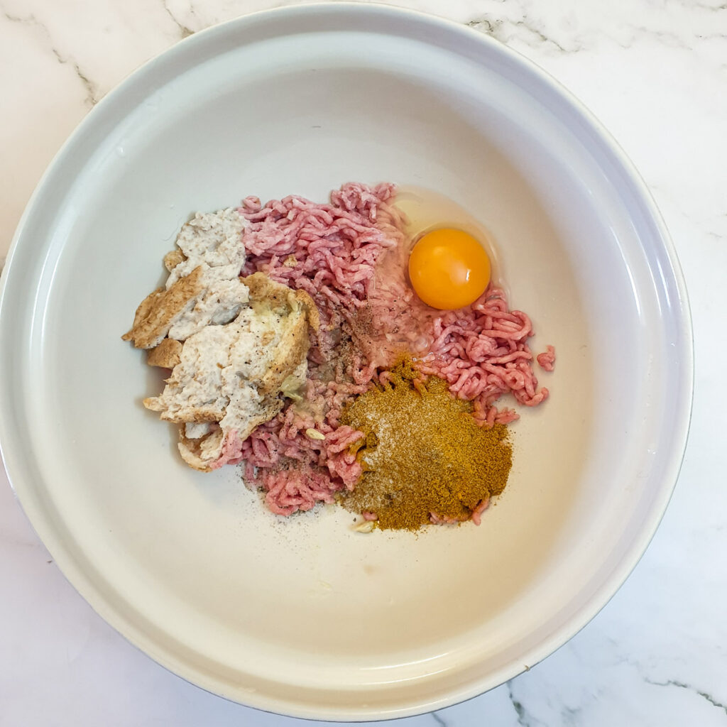 Ground meat, egg and spices in a mixing bowl.