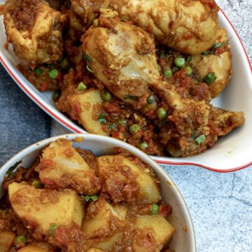 A dish of chicken bhuna made with chicken drumsticks, next to a side dish of Bombay potatoes.