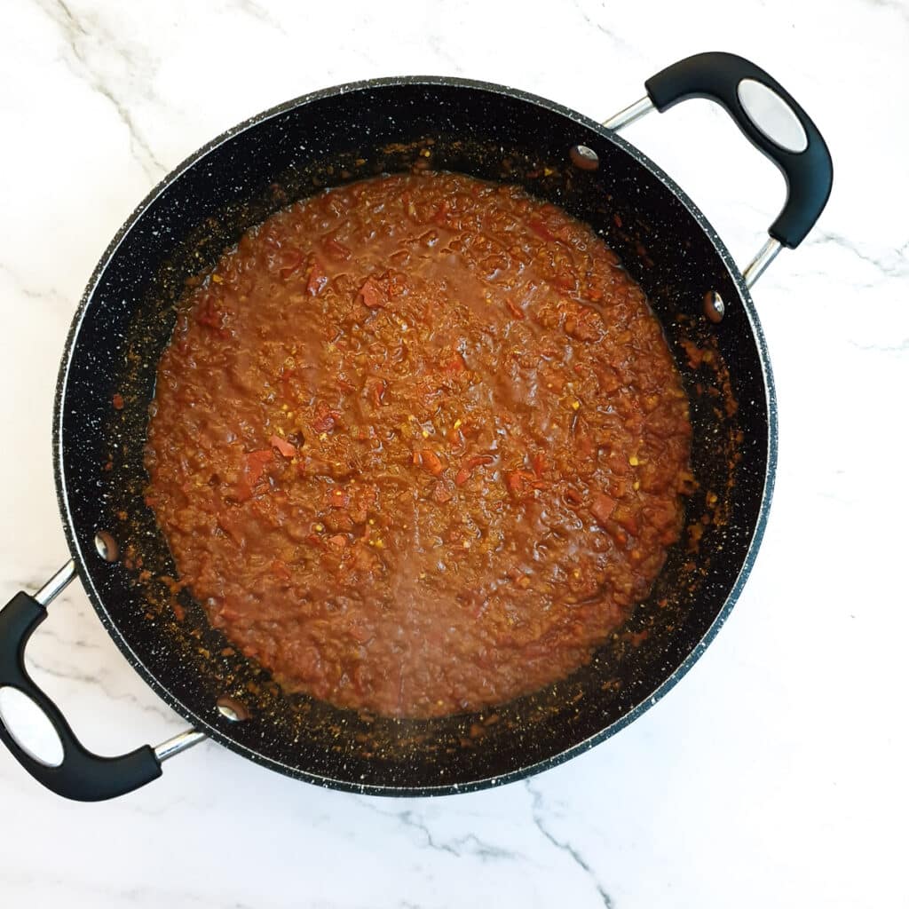 Red pepper and onion curry paste in a frying pan.