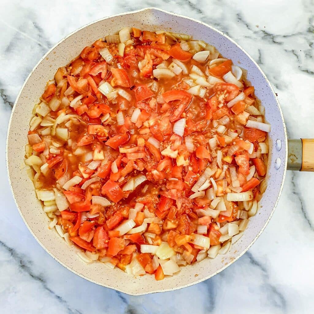 Chopped tomatoes and onions in a large frying pan.