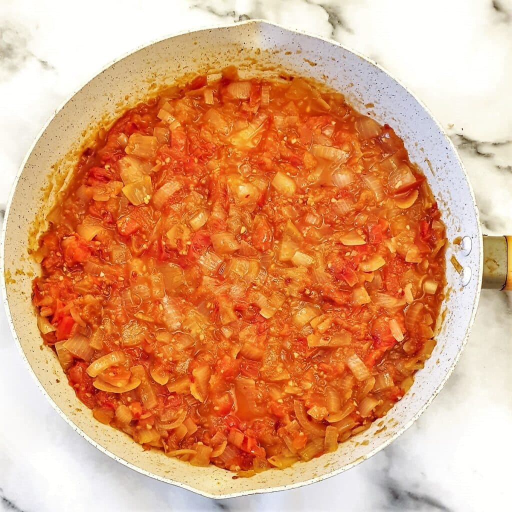 Tomato and onion sauce simmering in a frying pan.