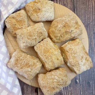 8 ciabatta rolls on wooden board.