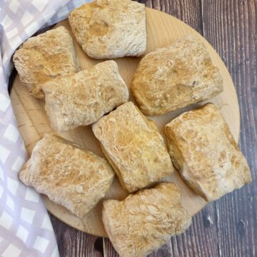 8 ciabatta rolls on wooden board.